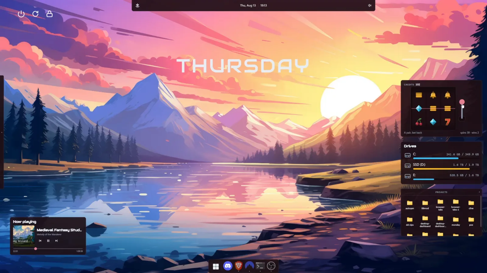 A DeskDash desktop over a sunset mountain wallpaper, with the day name across the sky, a slot machine widget, drive meters, a projects drawer and a now playing card.